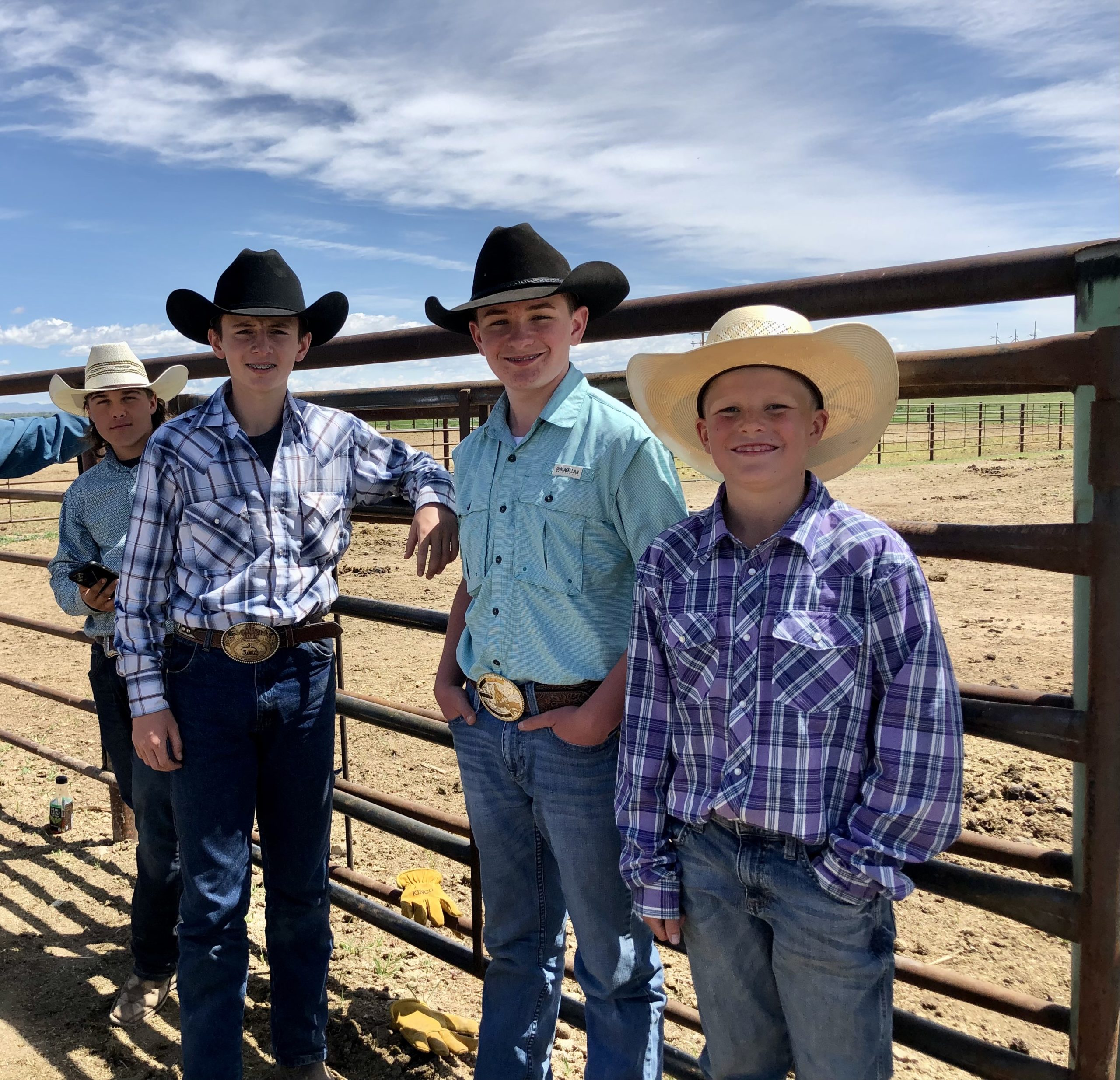 Three Boys Standing next to a corral